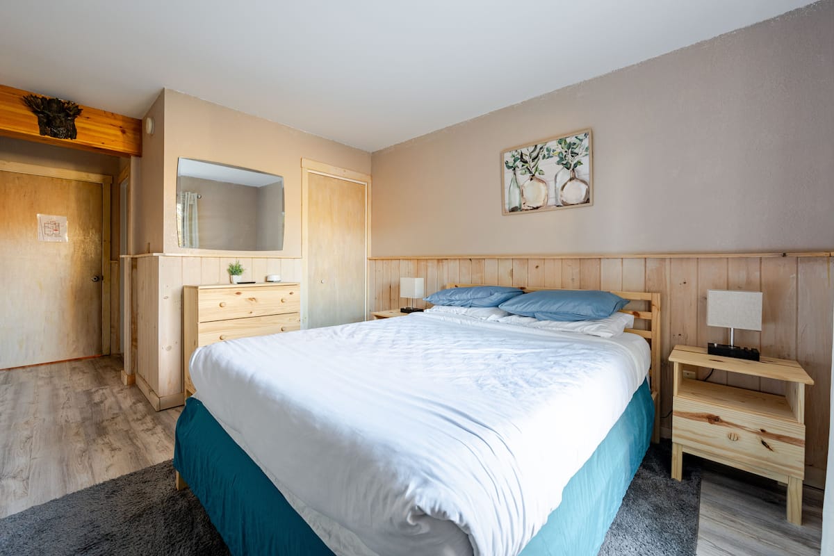 Primary bedroom with a queen bed, pine wainscoting, and a lamp on each side